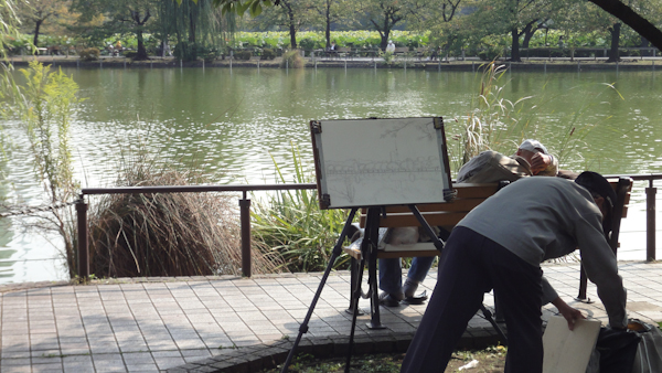 a painter at his easel overlooking the pond in Ueno PArk